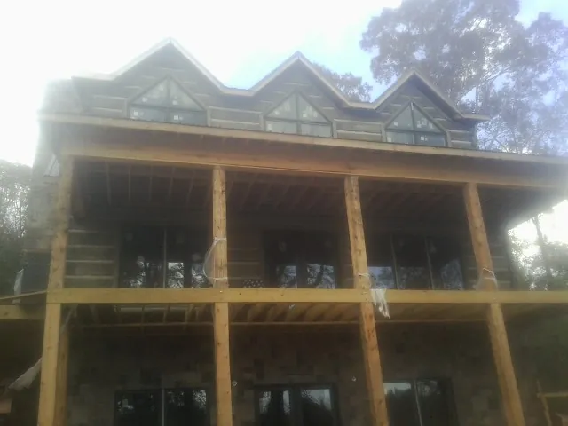 Dormers and porch framing on a large log home under construction — Roof Coating work by our crew in Kings Park