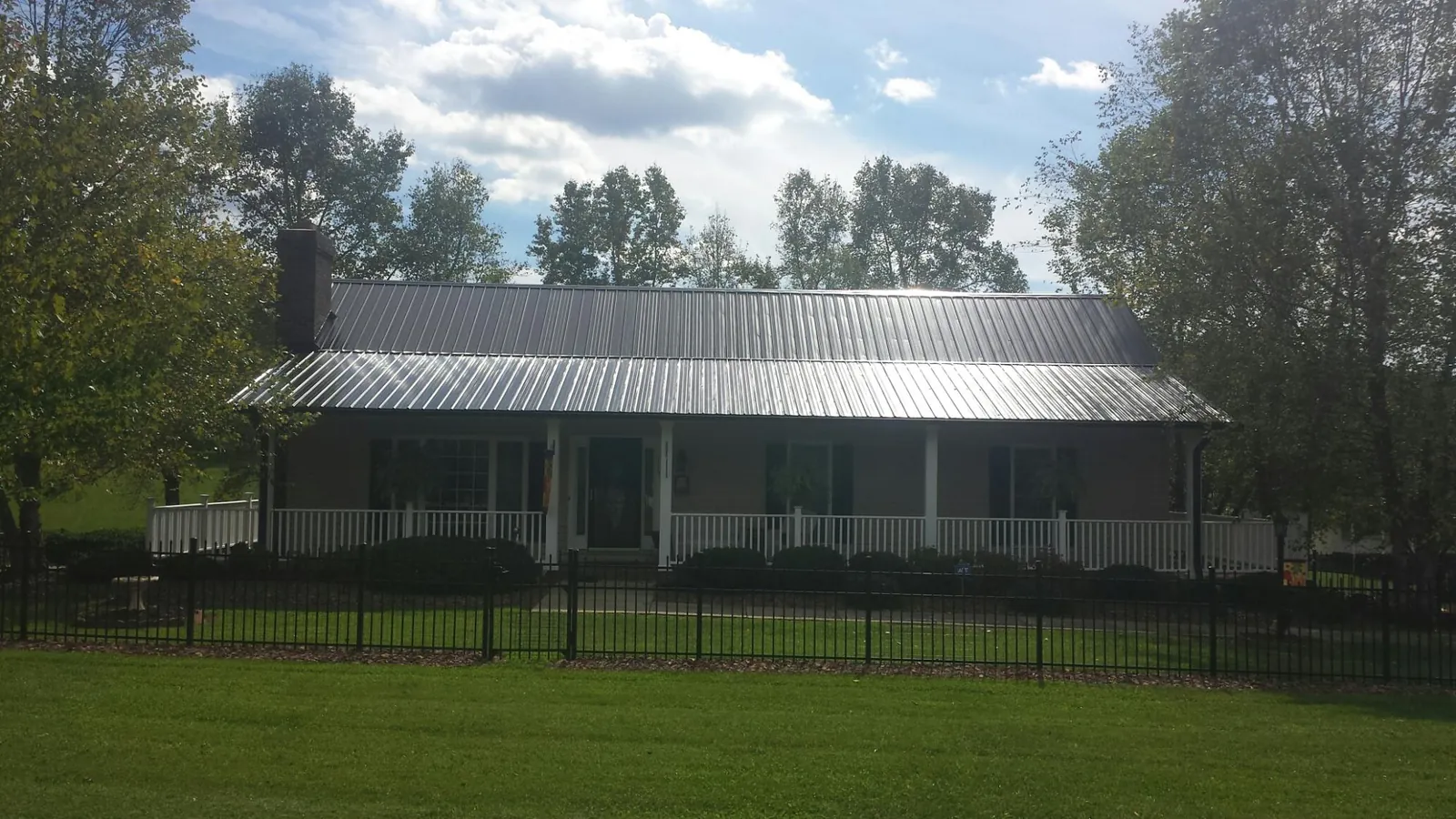 Gray metal roof on a brick ranch with a full width front porch — Gutter Guard Installation work by our crew in Kings Park