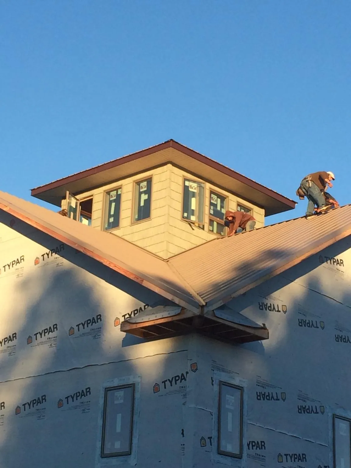 Roofers working around a rooftop cupola on a new metal roof at sunset — Roof Waterproofing in Kings Park by Roofing Brothers